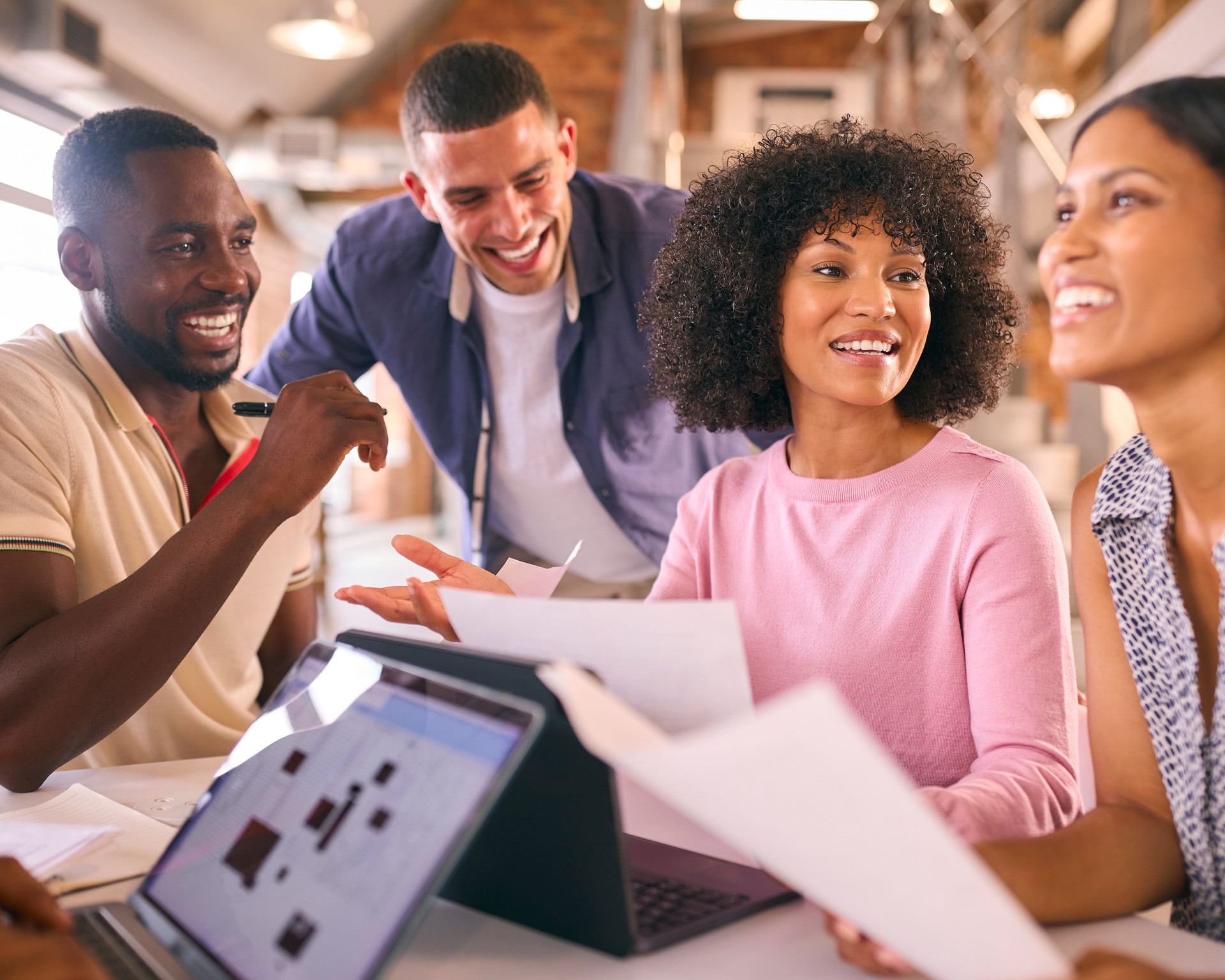 Multi-Cultural Business Team Meeting Around Desk In Modern Open Plan Office Discussing Documents